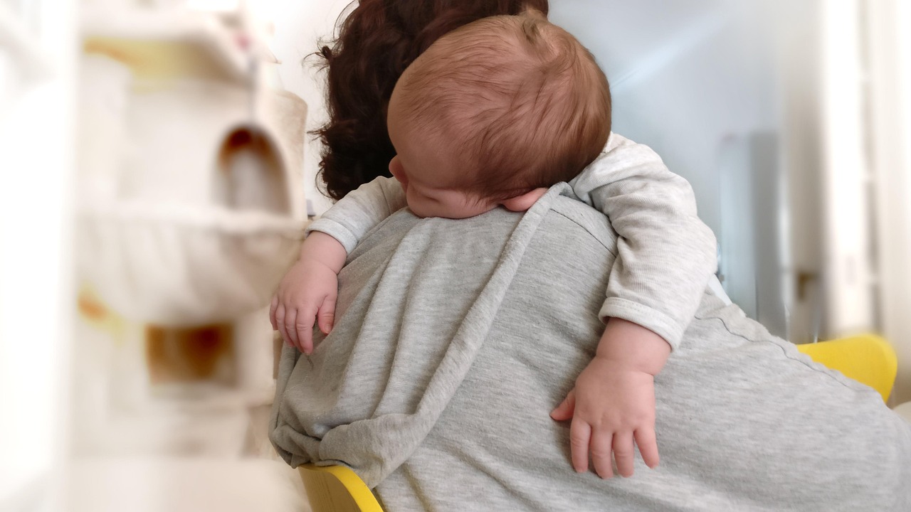 Infant sleeping peacefully against its mother